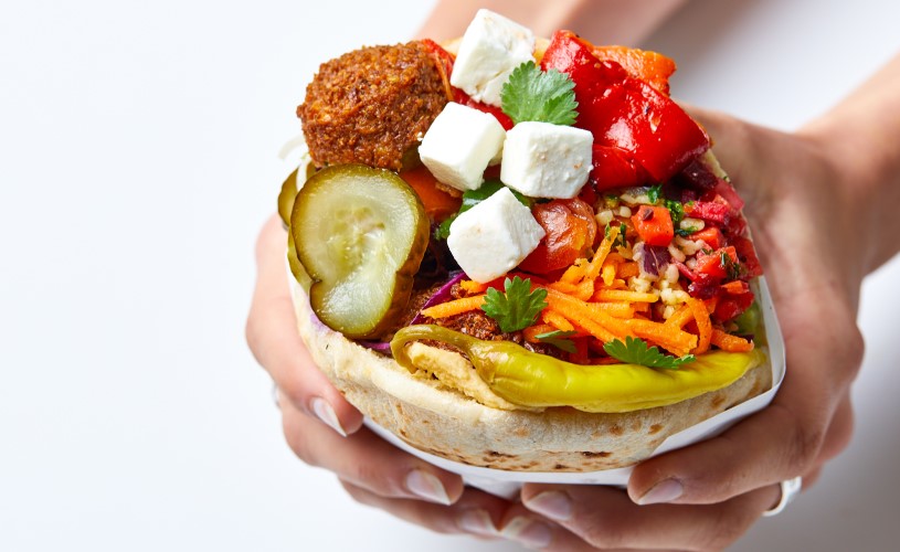 hand holding filled pitta with feta and falafel